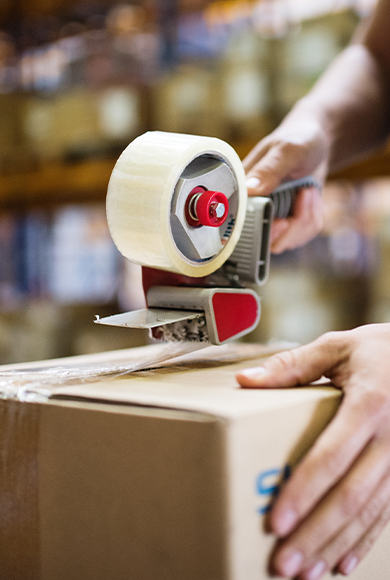 Male warehouse worker sealing cardboard boxes